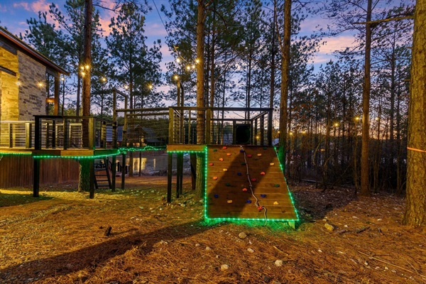 This treehouse-style play area features a rock climbing wall, elevated walkways, and glowing LED lights, offering fun for all ages. Nestled in a forest retreat, it's a dream for families looking for a cabin rental with an exciting kids’ play area