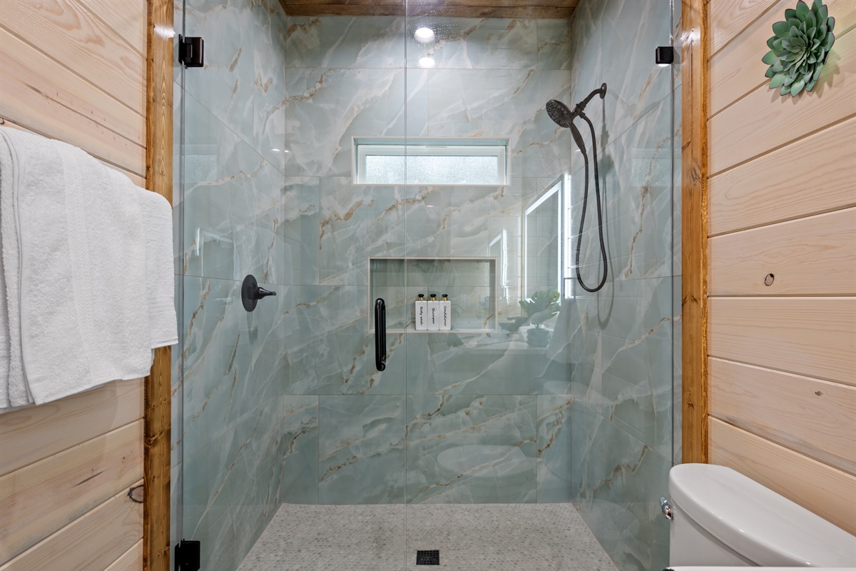 A large walk-in shower with beautiful tilework adds a clean, modern touch to the bathroom while still fitting perfectly with the cabin’s rustic style.