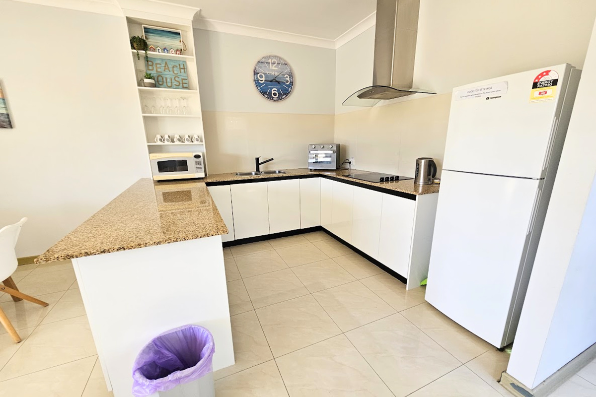 Large kitchen with electric stove top, full size fridge and coffee machine