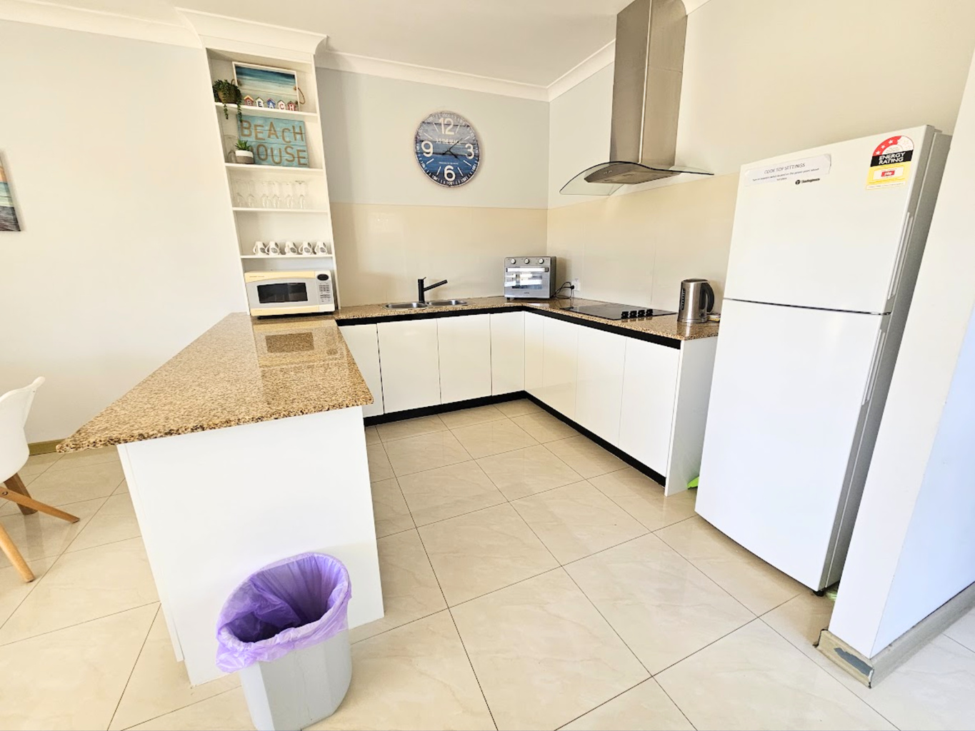 Large kitchen with electric stove top, full size fridge and coffee machine
