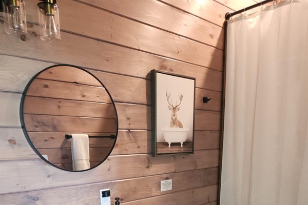Full bathroom with round mirror, shelf space, and tasteful decor.