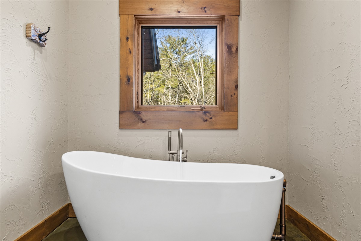 The freestanding tub offers a serene spot to unwind while soaking in peaceful surroundings.