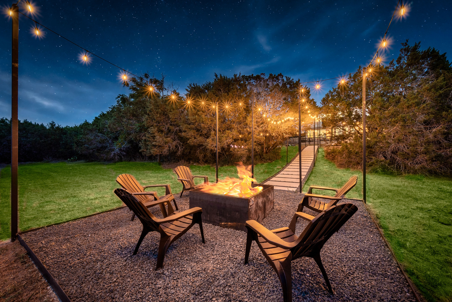 Fire pit patio set beneath twinkling string lights — perfect for evenings outdoors.