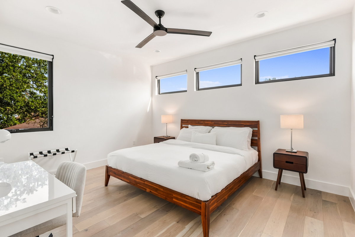 Sunlit bedroom with a wood platform bed and a wall of picture windows.