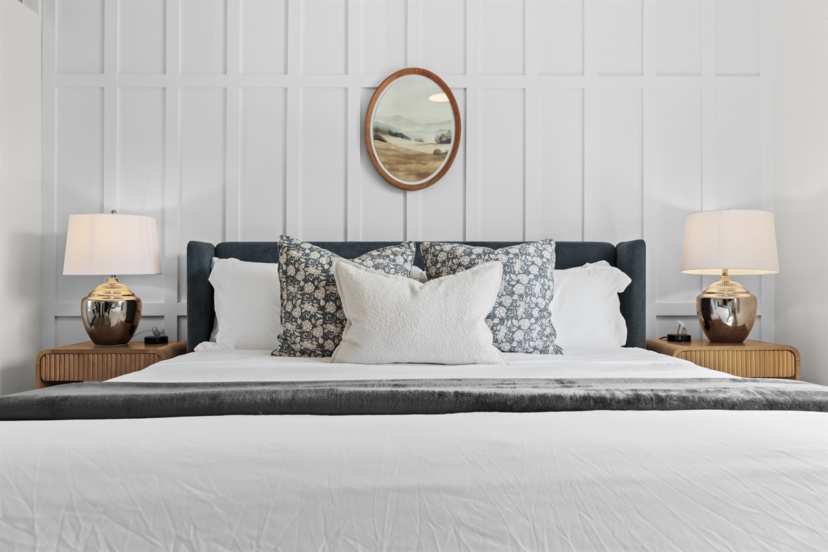 Luxurious king bed with soft linens and modern panel wall backdrop.