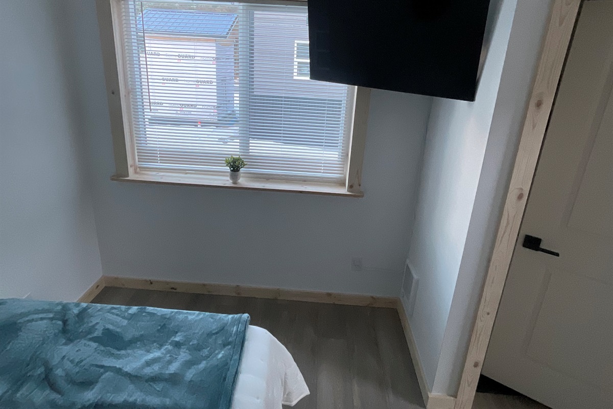 Bedroom on main floor includes a Queen Size Bed with night stand, closet space, and TV. [Photo is representative but may not be from this cabin].