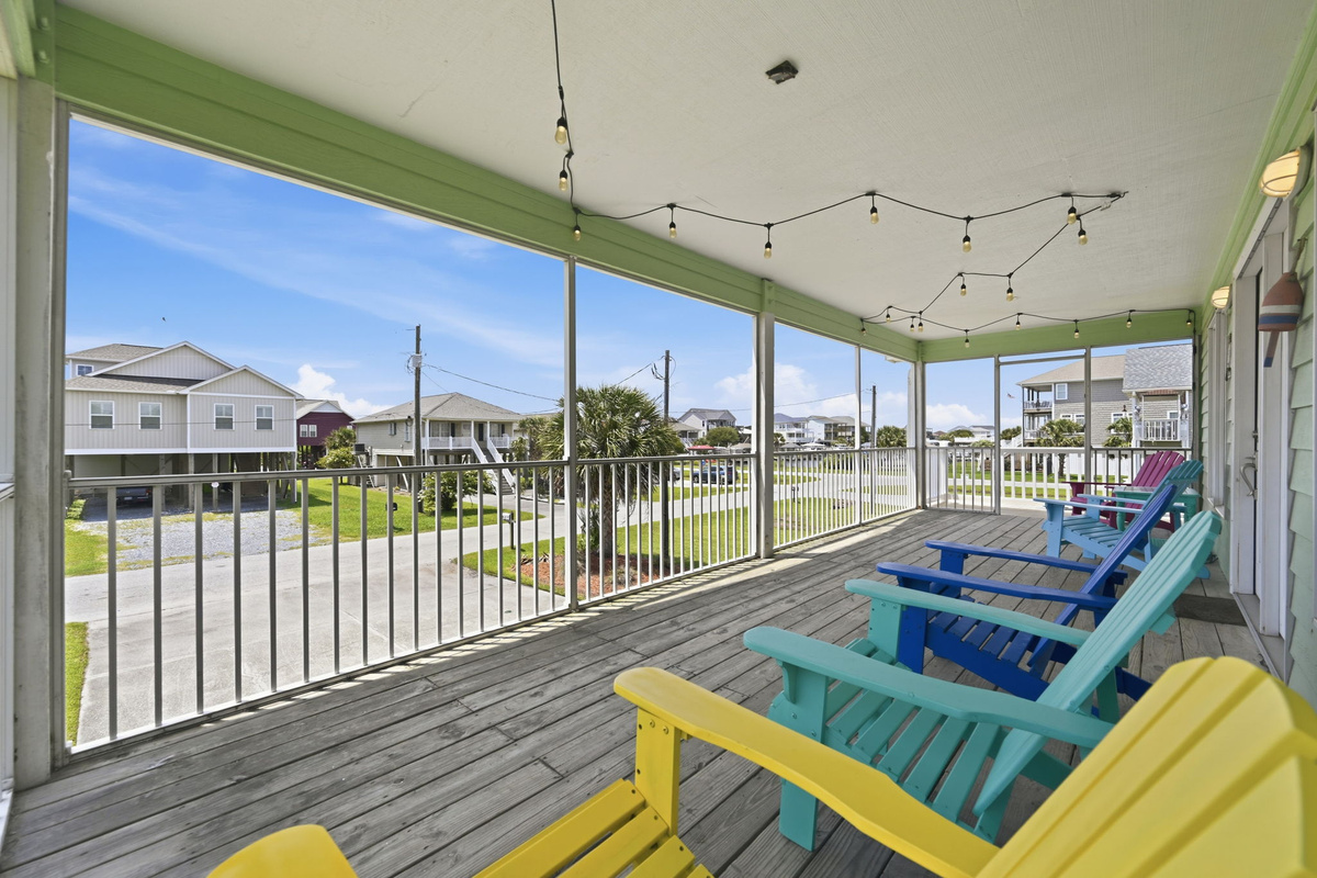 Spacious screened-in porch with colorful Adirondack chairs, perfect for relaxing and enjoying the coastal breeze