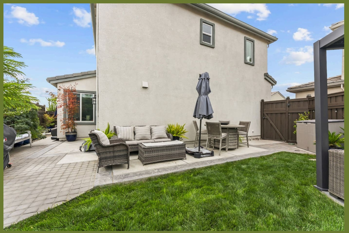 Backyard patio with lounge seating, umbrella shade, and open lawn space for relaxing outside.