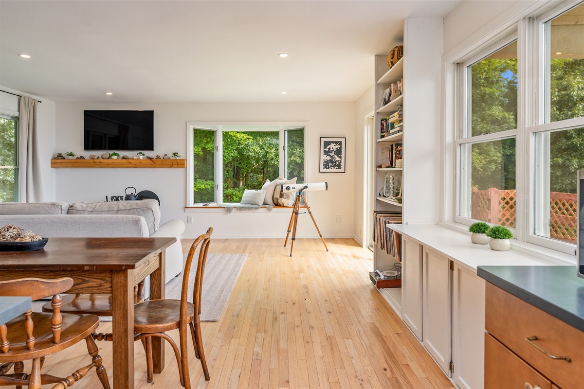 Bask in natural light from the oversized windows in this cozy, open-concept living area surrounded by forest