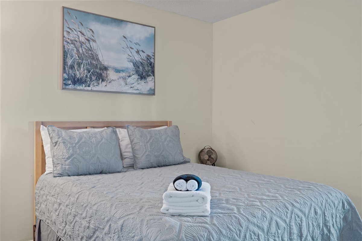 Bright bedroom with coastal artwork, crisp linens, and a calm, uncluttered layout for easy, comfortable nights