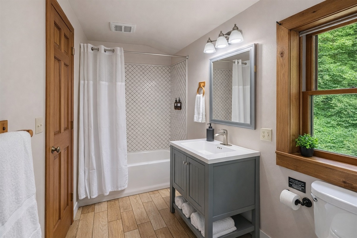 Upstairs full bathroom featuring a tub/shower combo with tile surround, fresh white linens, and a spacious vanity with plenty of storage — bright, clean, and stocked with essentials for a comfortable stay at Cosmic Ridge Retreat.