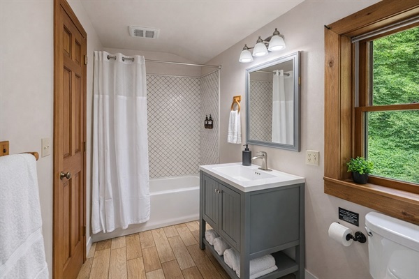 Upstairs full bathroom featuring a tub/shower combo with tile surround, fresh white linens, and a spacious vanity with plenty of storage — bright, clean, and stocked with essentials for a comfortable stay at Cosmic Ridge Retreat.
