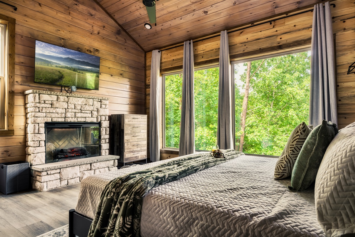 Bedroom with stone fireplace and large Nature-facing windows