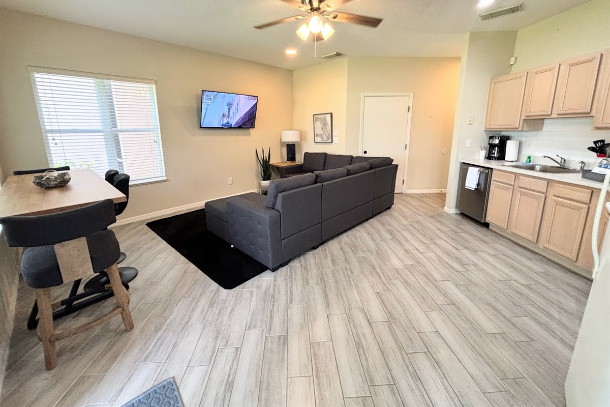 Open living and dining space with updated flooring, cozy seating, and a bright kitchen layout.