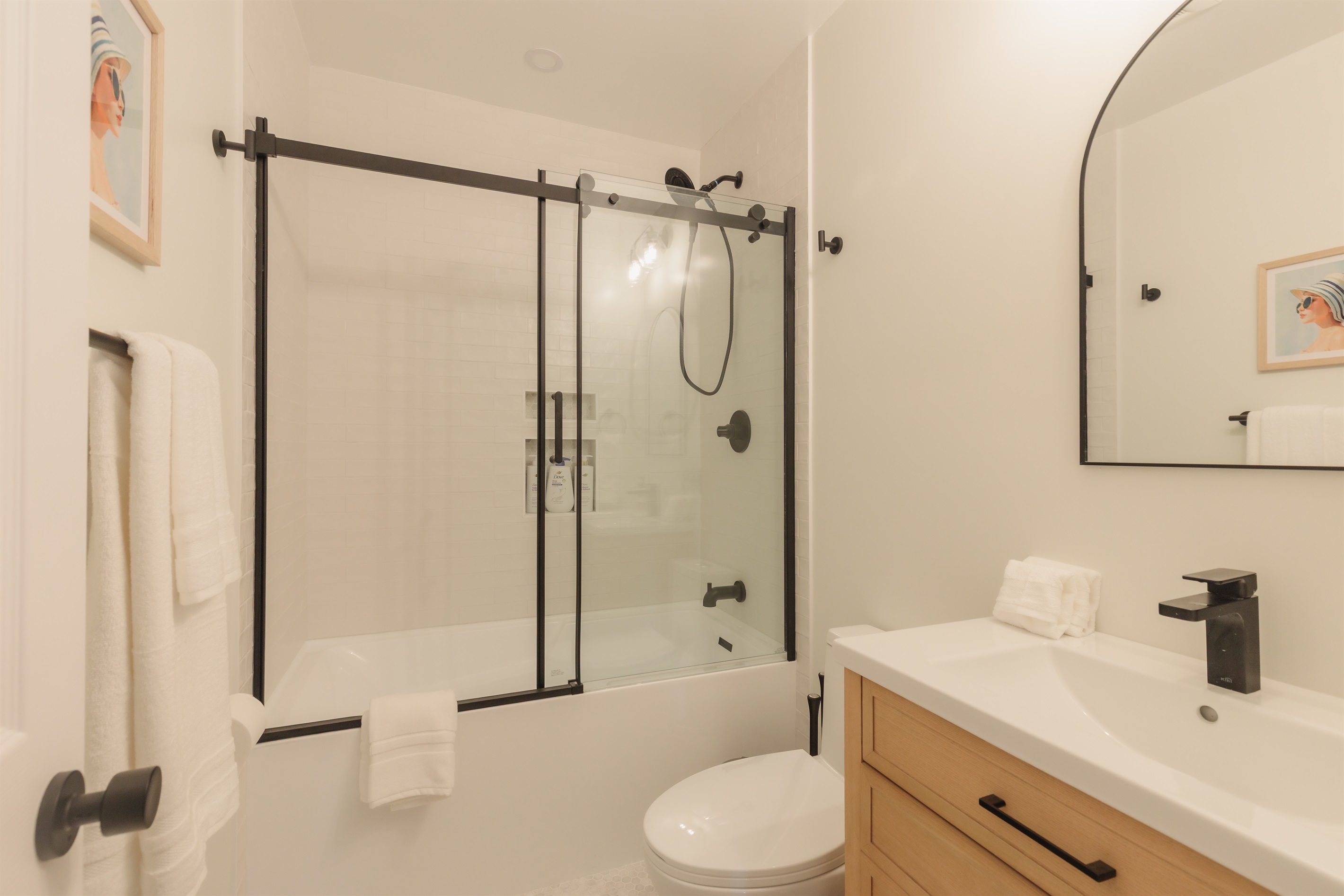Refresh in style: this modern bath features a sleek glass‑sliding shower/tub, matte‑black fixtures, and hotel‑quality towels to help you unwind after a day exploring San Diego