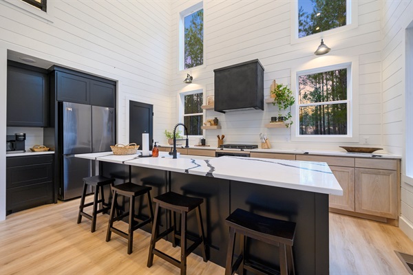 Soaring ceilings and walls of windows fill the open-concept kitchen with natural light and forest views.