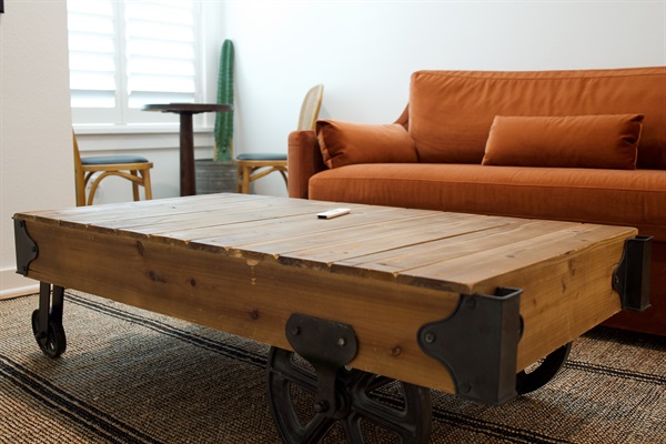 Rustic wood coffee table with industrial metal wheels that completes the rebel, western railroad themed living space and adds a bold focal point to the room.