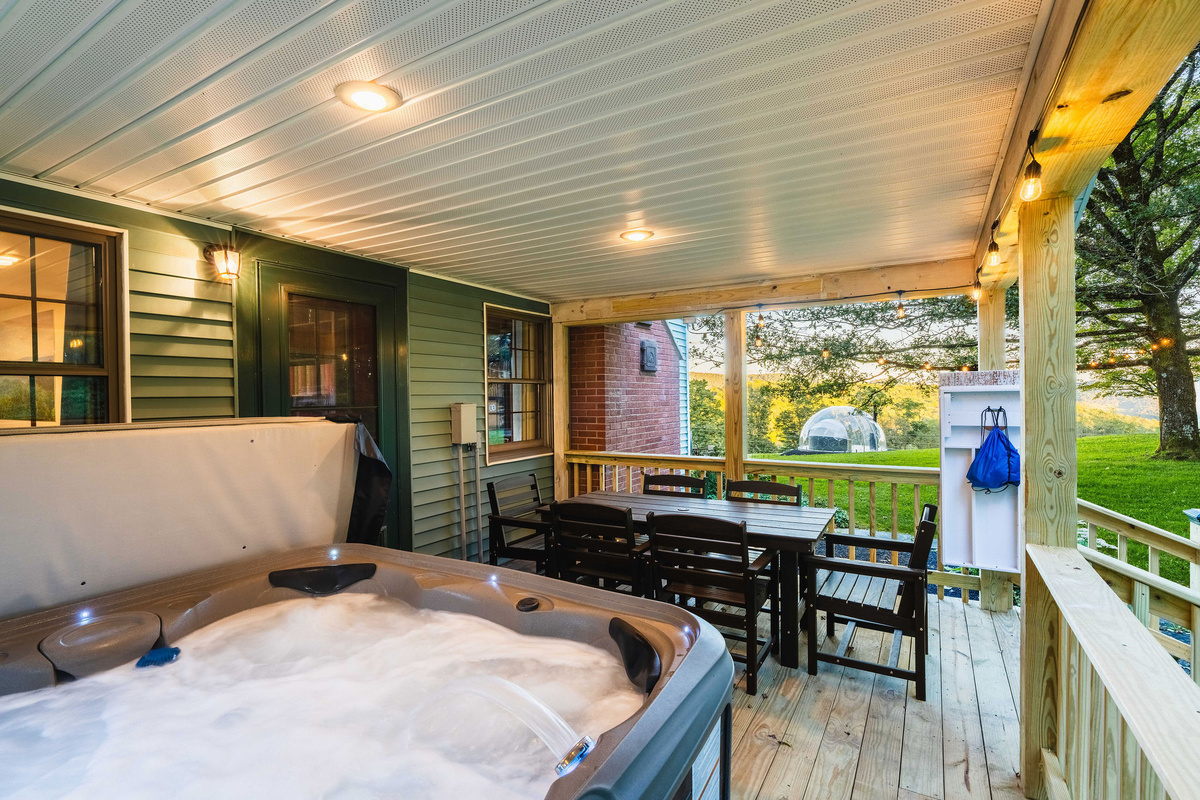 🌅 Covered deck with the hot tub, dining table and a clear