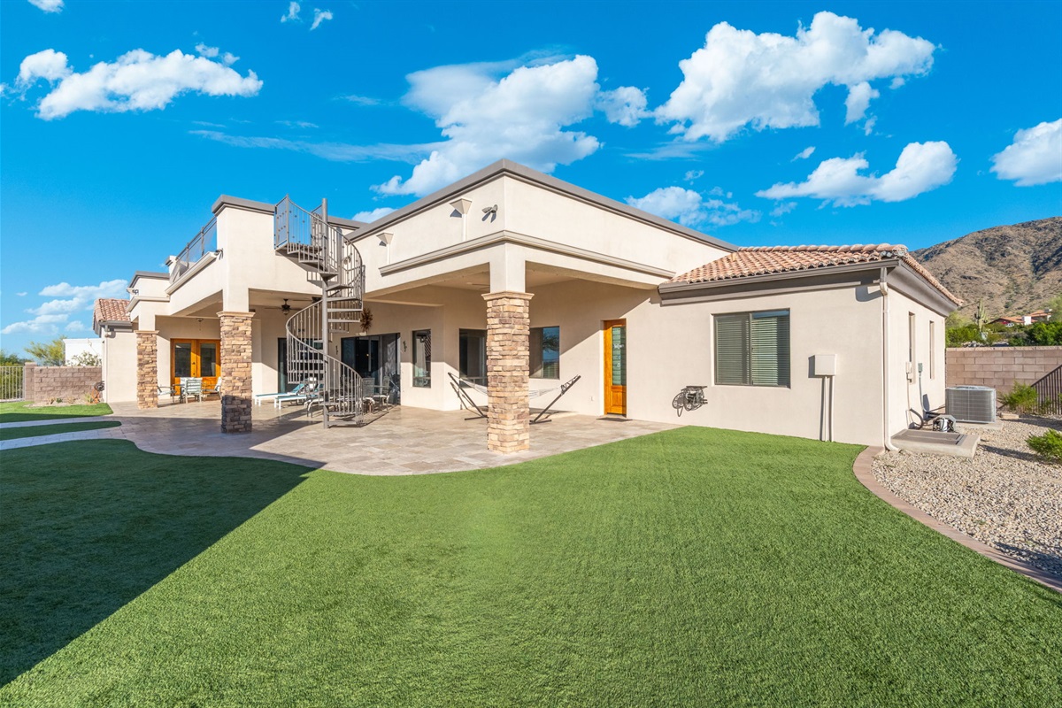 Wide exterior view highlights the home’s private estate setting and beautifully designed outdoor gathering spaces