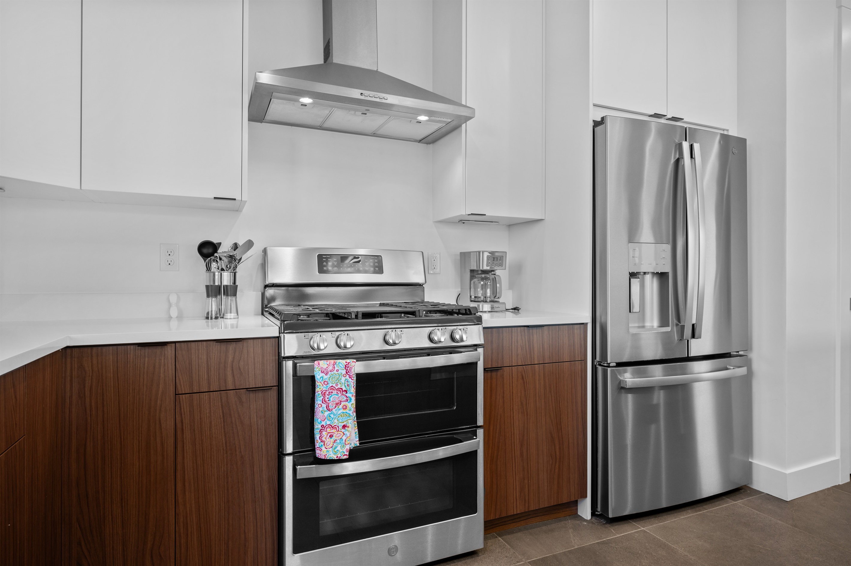 Gourmet kitchen with sleek stainless appliances and vented range hood.