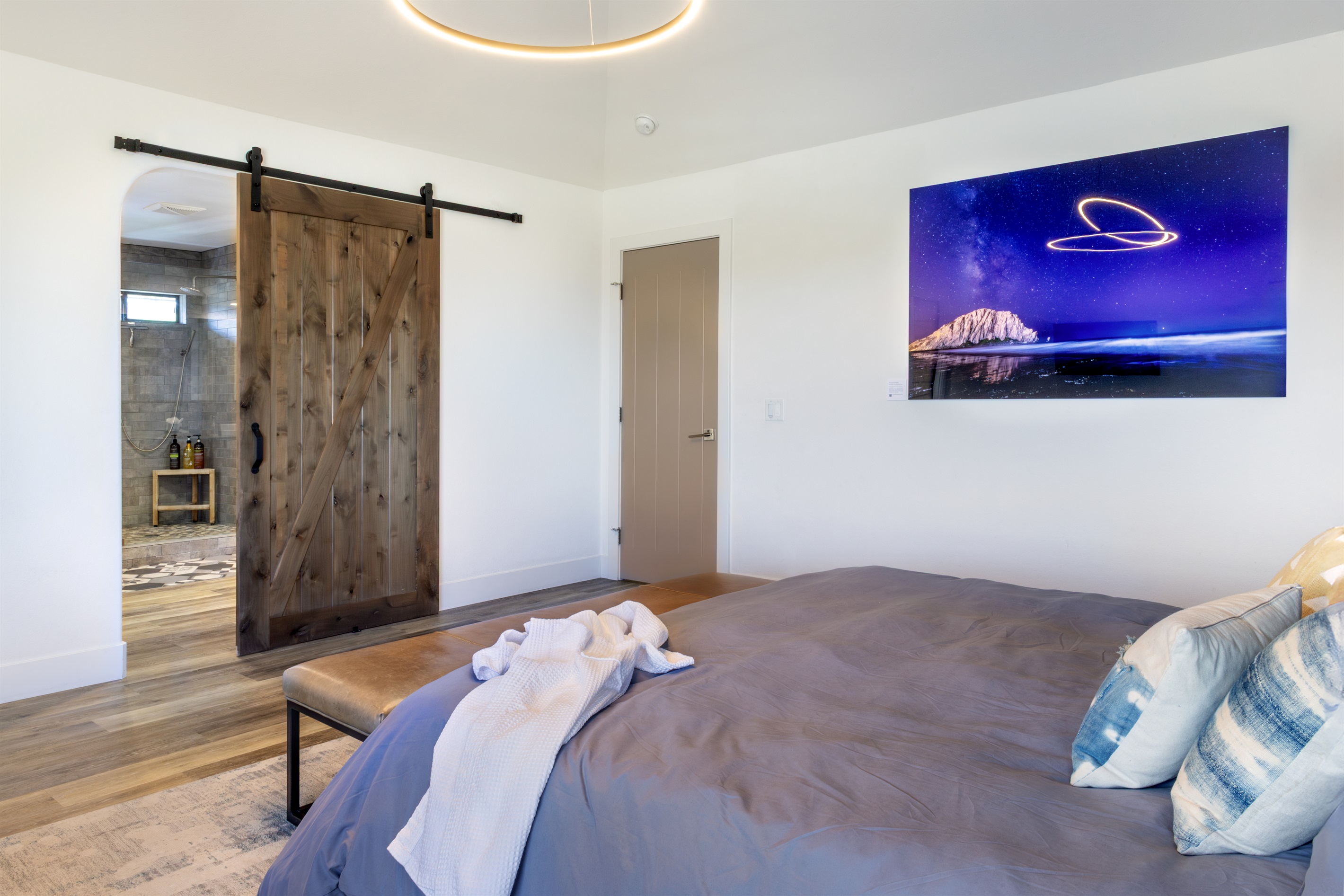 Rustic charm meets modern luxury — a hand-crafted sliding barn door opens to the en suite bath, while a stunning night-sky art piece brings the California coast indoors.