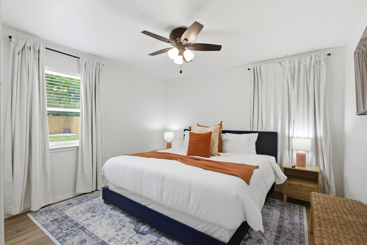 Bedroom 2 with King Bed dressed in warm tones, Ceiling Fan, and large windows. A bright and quiet retreat in the heart of Arlington.

