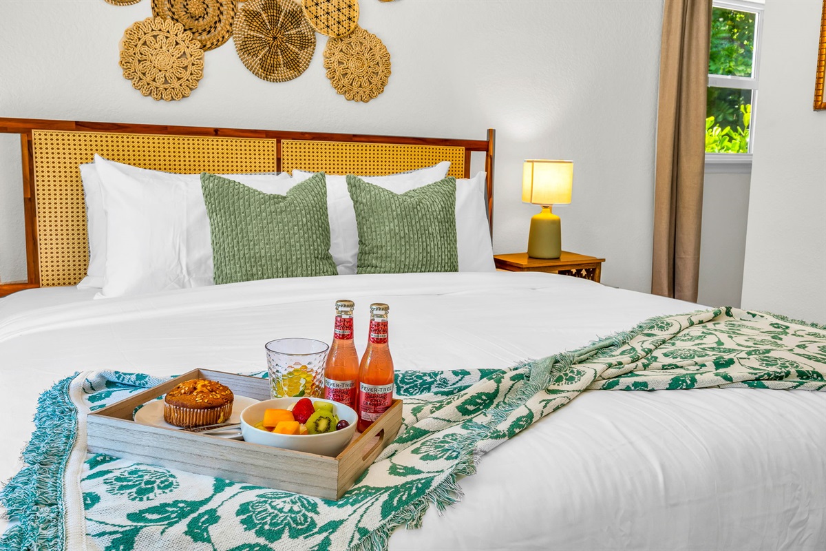 Serene ensuite primary king suite featuring a plush bed with luxury linens, vaulted ceilings with exposed beams, and elegant coastal décor. Includes a spacious walk-in closet with washer and dryer for added convenience and comfort.