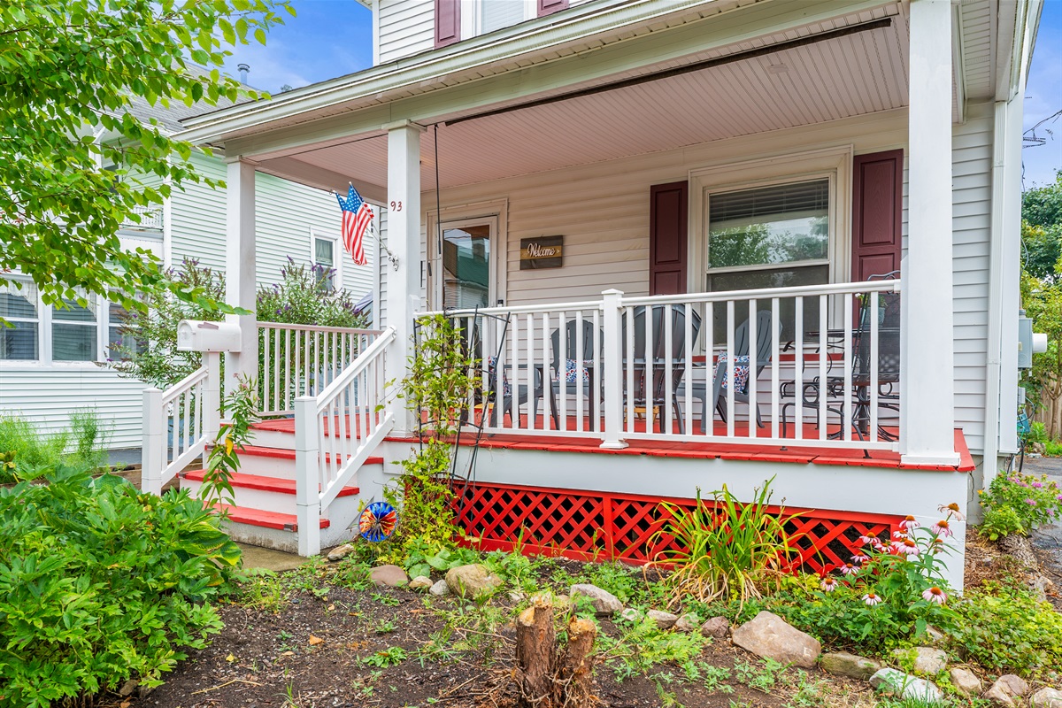 Enjoy summer evenings on this spacious front porch with Adirondack seating and patriotic charm. 🇺🇸