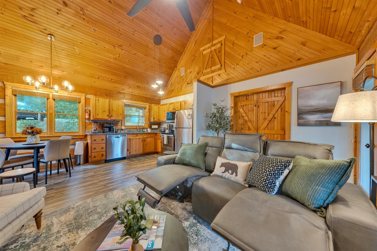 Open-concept living room with vaulted ceilings, zero gravity recliners, and a fully equipped kitchen