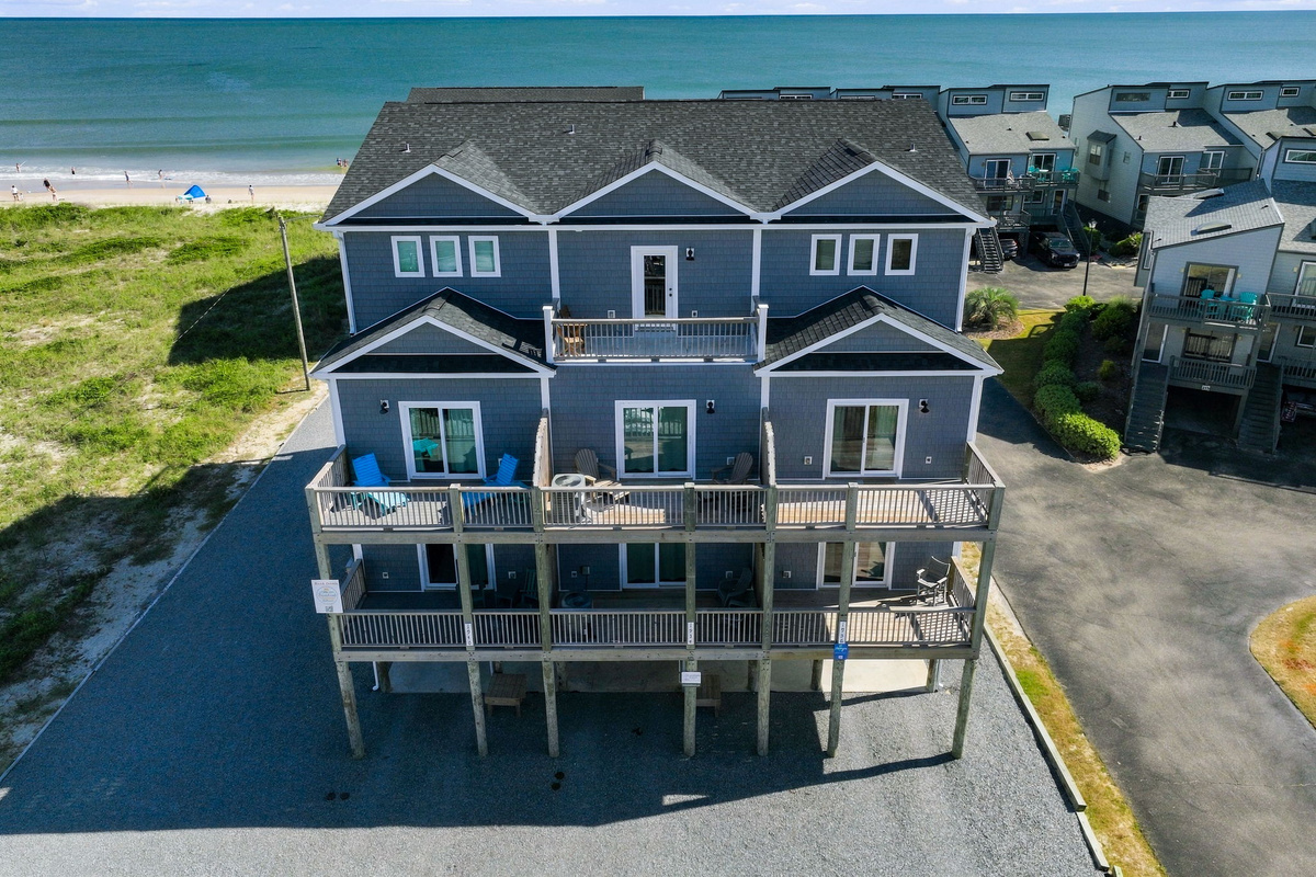Aerial view highlighting the direct oceanfront location of the multi-story complex, showcasing immediate proximity to the sandy beach and ocean shoreline.   