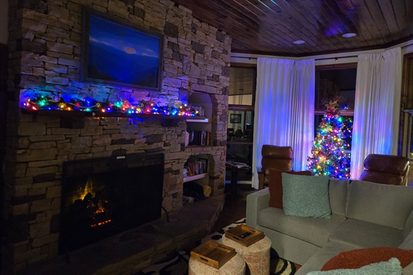 A Cheerful Living Room Adorned with Festive Lights, a Crackling Fireplace, and a Vibrant Christmas Tree. A Perfect Recipe to Enjoy the Holiday Season.