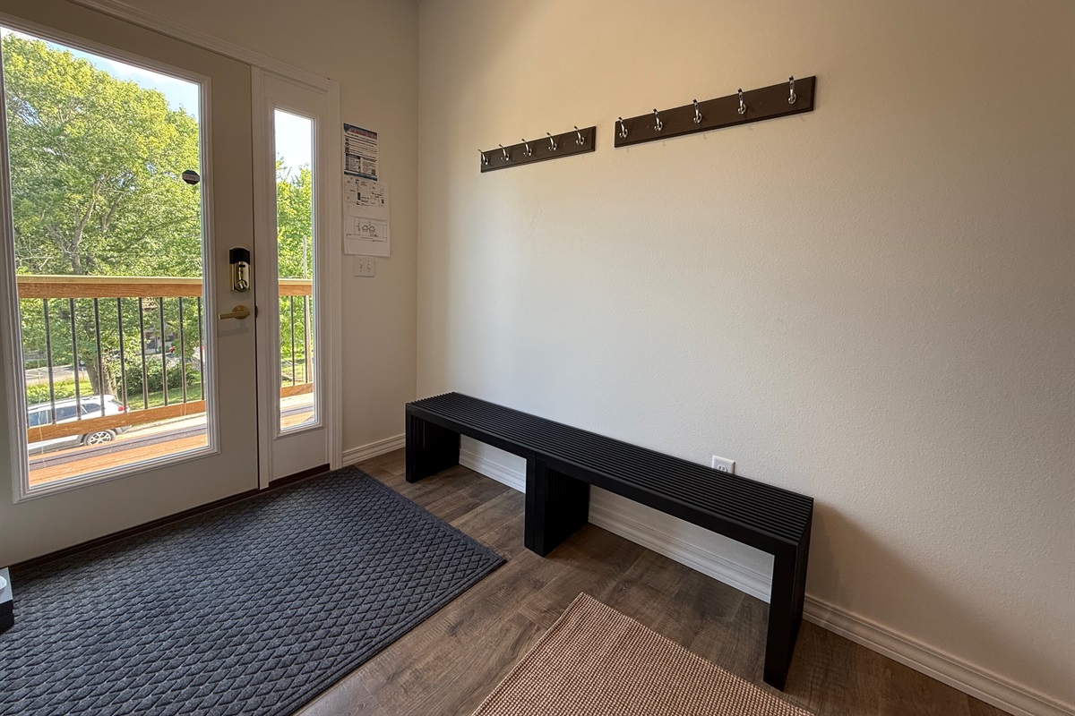 Seating for putting on shoes and coat hangers conveniently
 placed above 