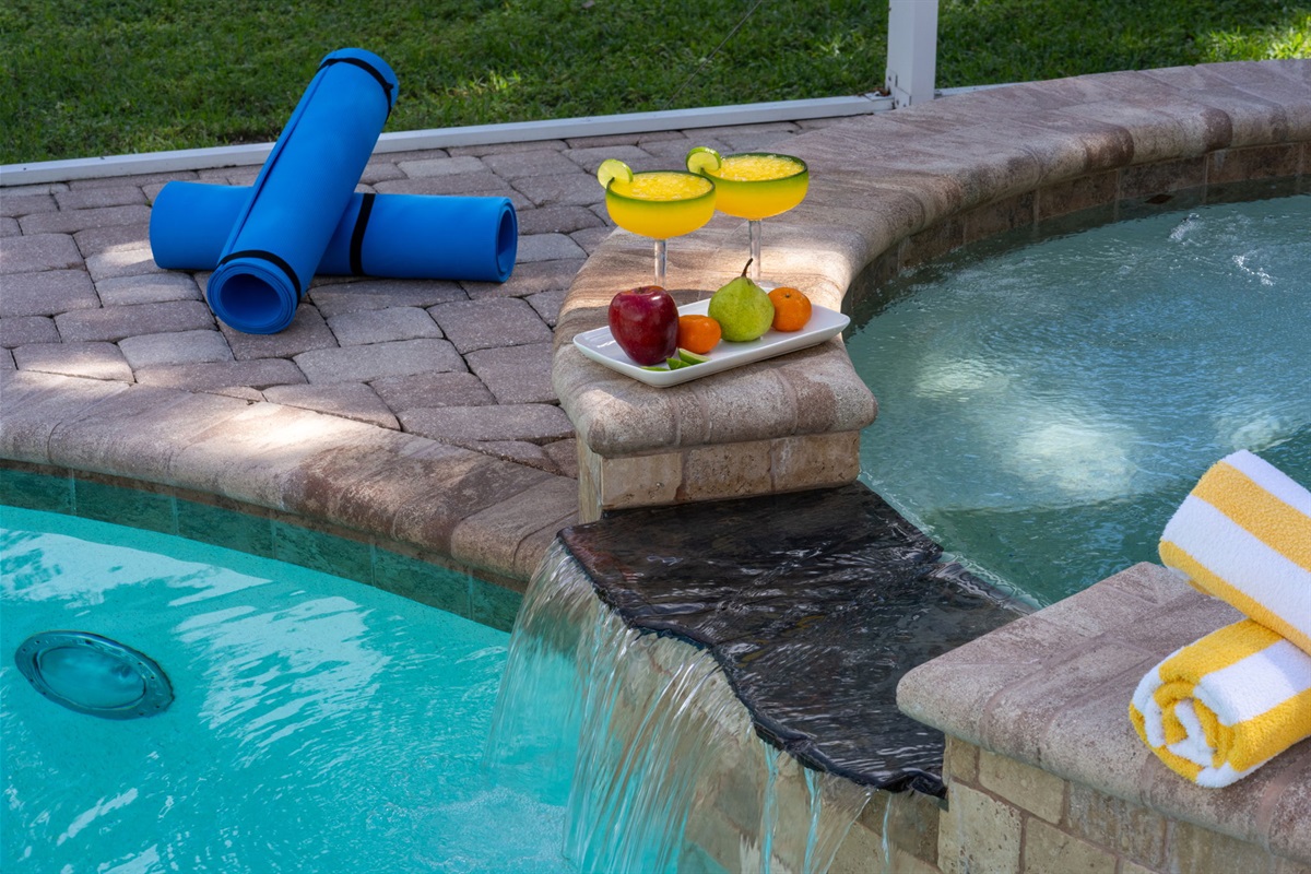 Serene spa with cascading waterfall feature flowing into the pool.