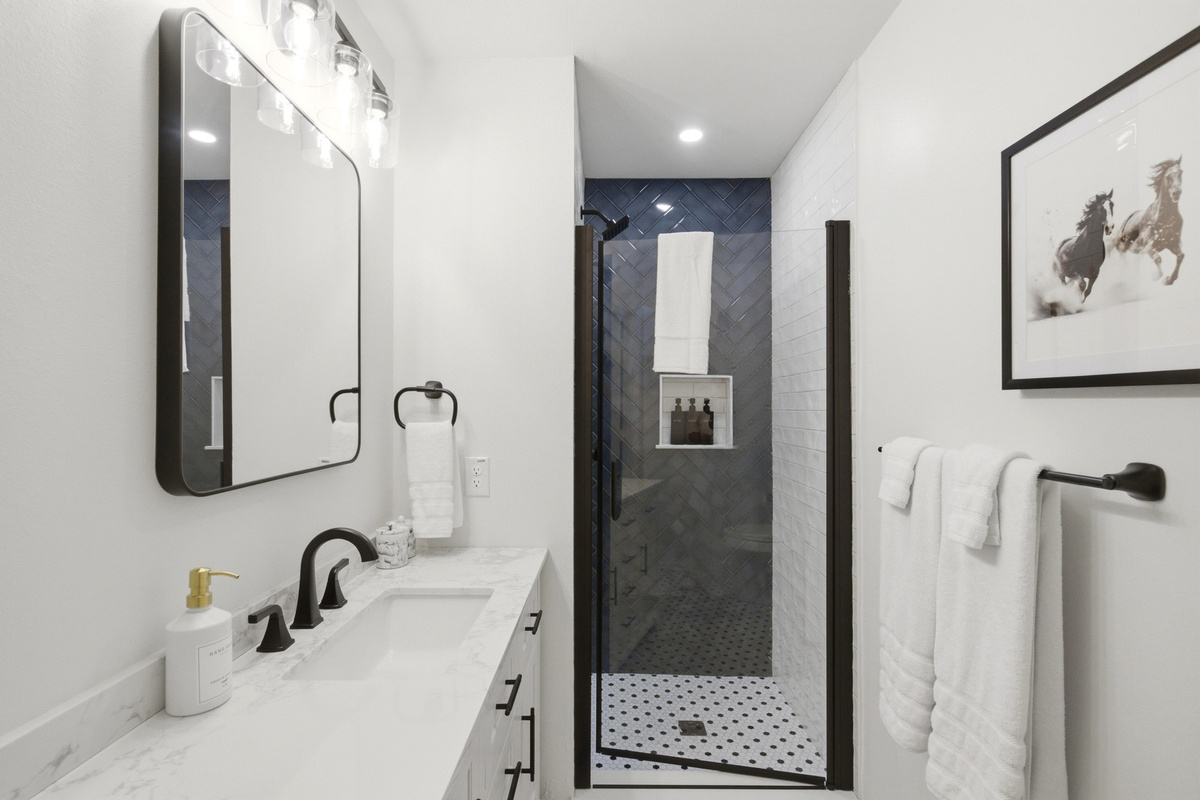 Spacious Bathroom 2 with bright Single Vanity, large mirror, and Standing Shower. Stocked with essentials by Ginger Lily Farms, fresh towels, and Hairdryer.

