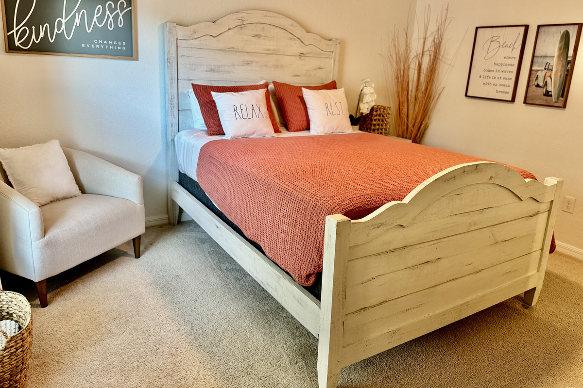 Second bedroom—queen bed, TV, accent chair.