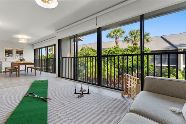 “Bright Sunroom + Game Lounge featuring oversized windows, casual seating, and family-friendly games — the perfect spot for morning coffee, naps, board games, putting practice, or rainy-day fun.”