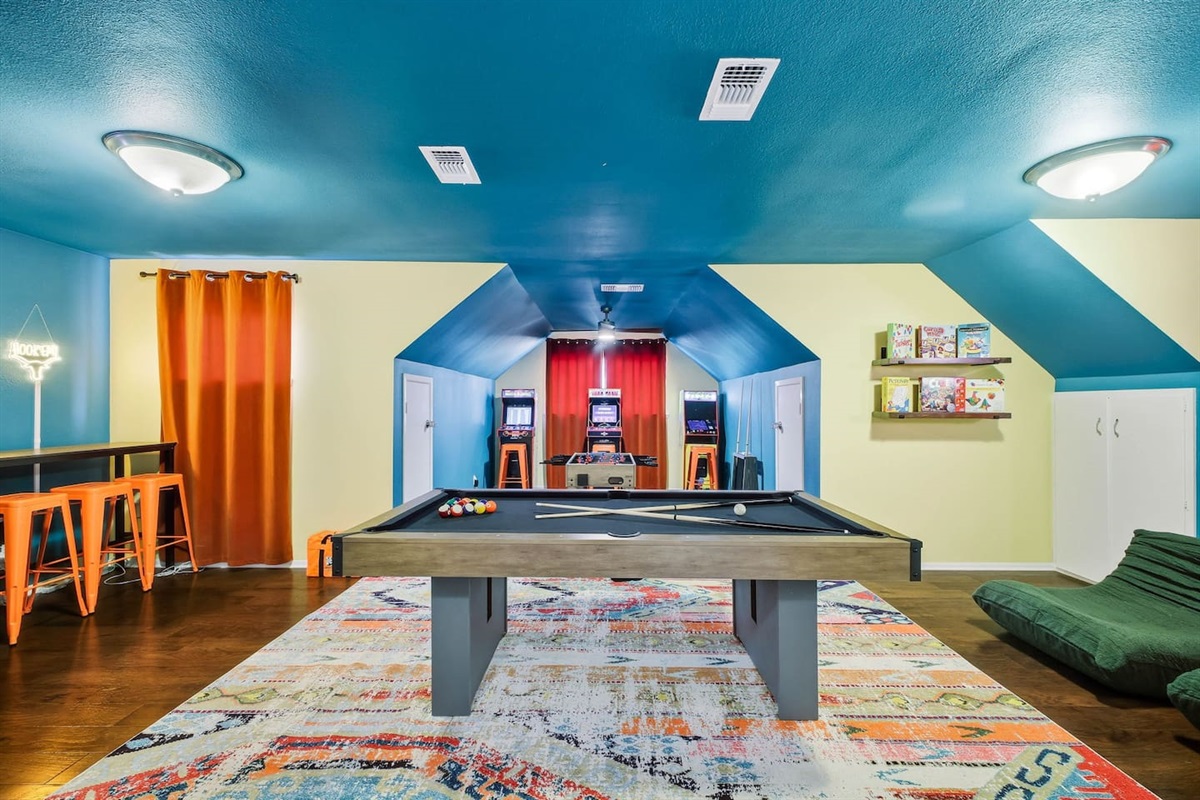 Upstairs game room with arcade machines, pool table, foosball and large Roku TV 
