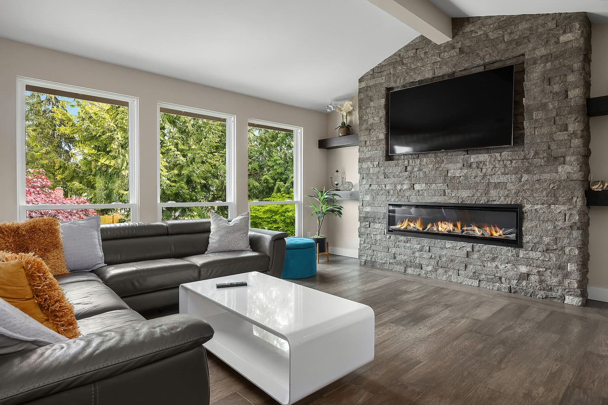 “A spacious living room with a large TV and a warm, modern fireplace, offering the ideal spot for movie nights and cozy evenings.”