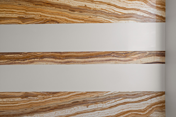 Custom striped wall design blending sleek white panels with warm, desert-veined stone tile accents