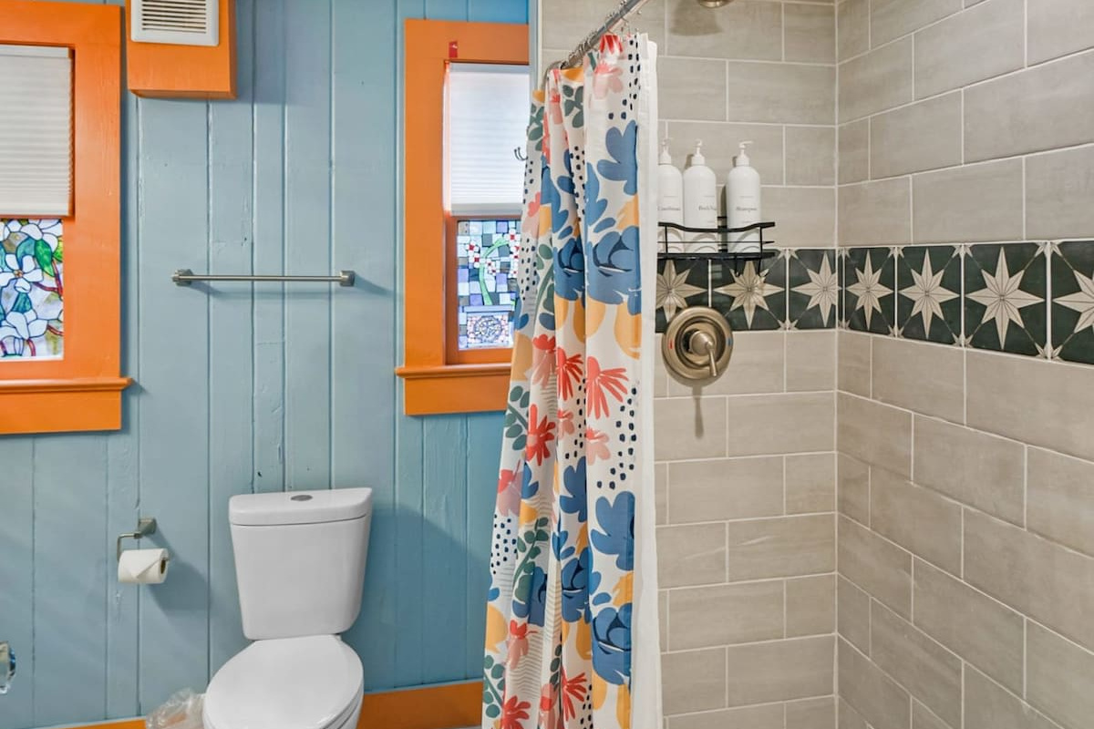The walk-in shower is tiled from floor to ceiling with a low step in, framed by that warm orange trim. Small, bright, and exactly what you want after a long morning spent between the sand and the Atlantic.