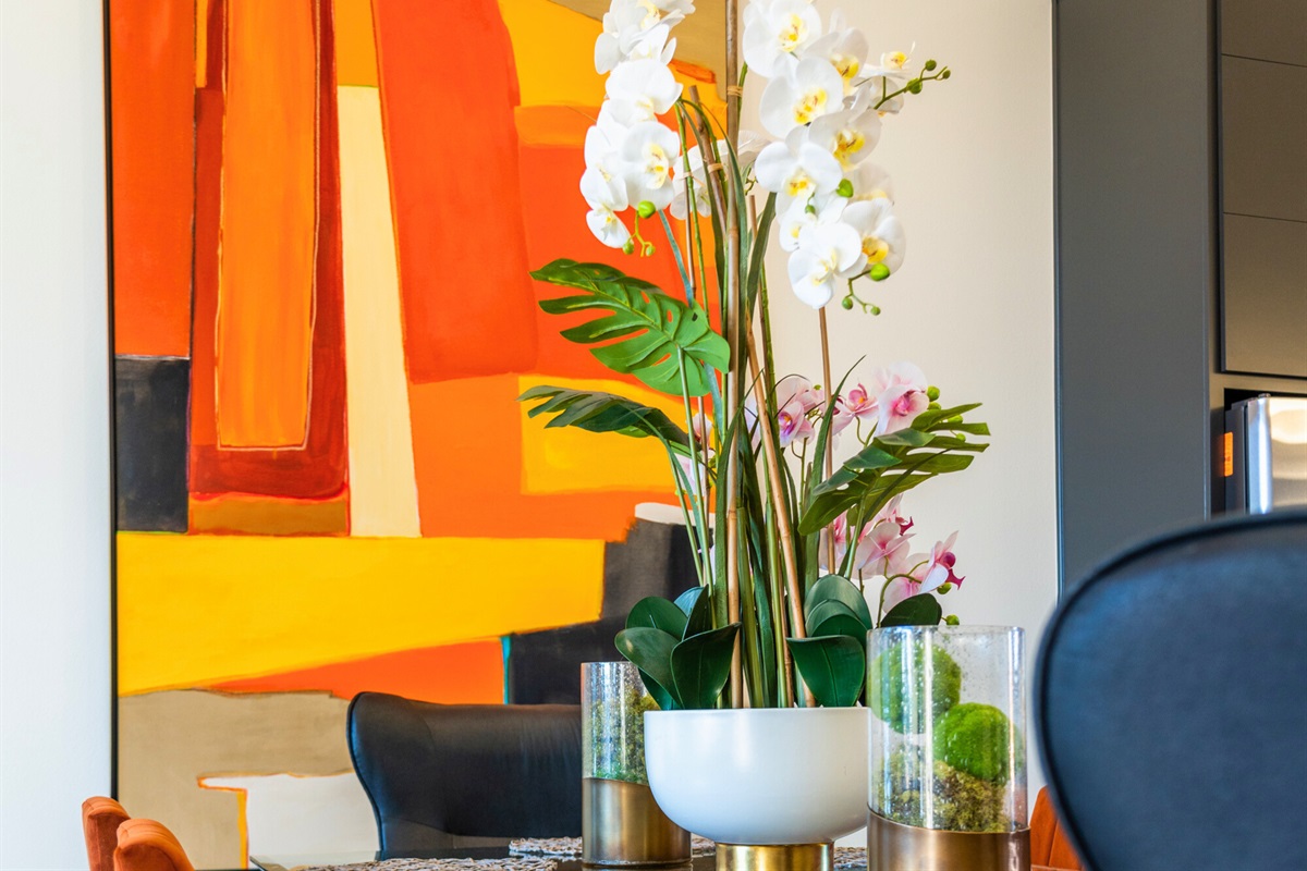 This dining area comes alive with bold, vibrant artwork, a stunning floral centerpiece, and an effortlessly modern yet welcoming ambiance for every gathering.