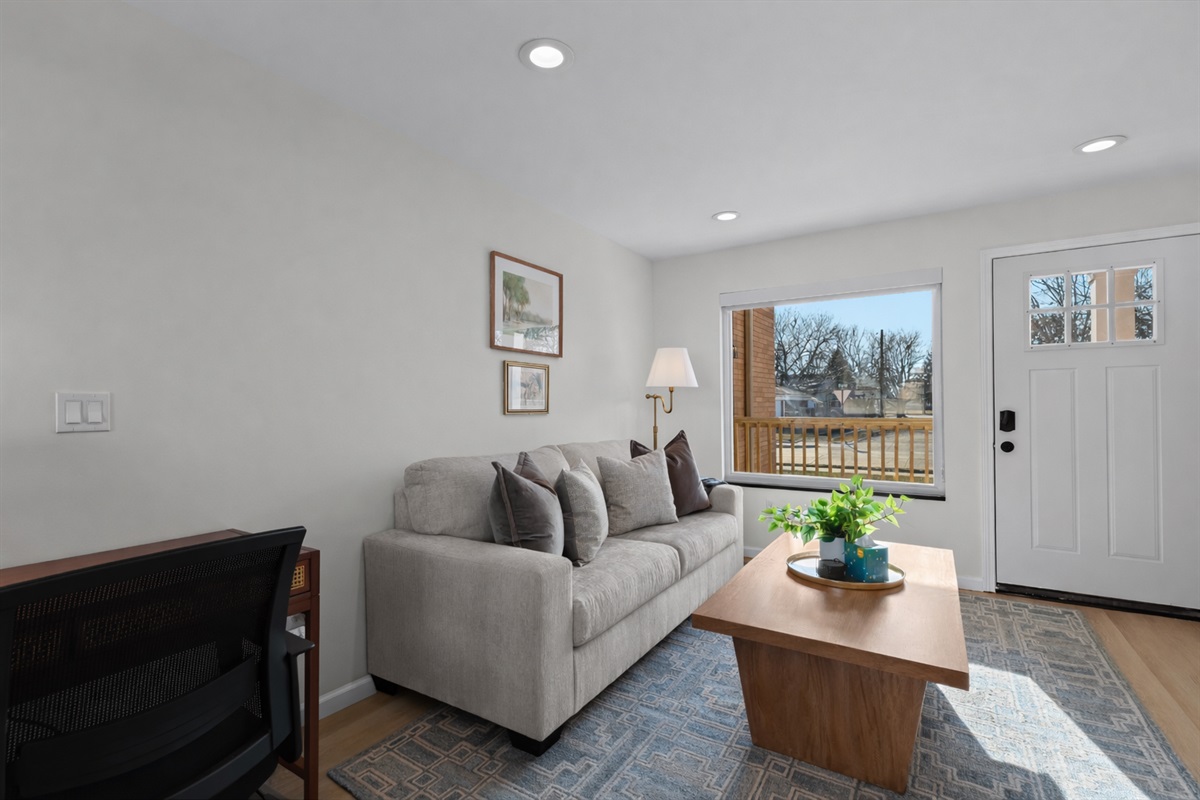 Bright, modern living room with plush seating, clean lines, and a large window that fills the space with natural light and a warm, welcoming feel.