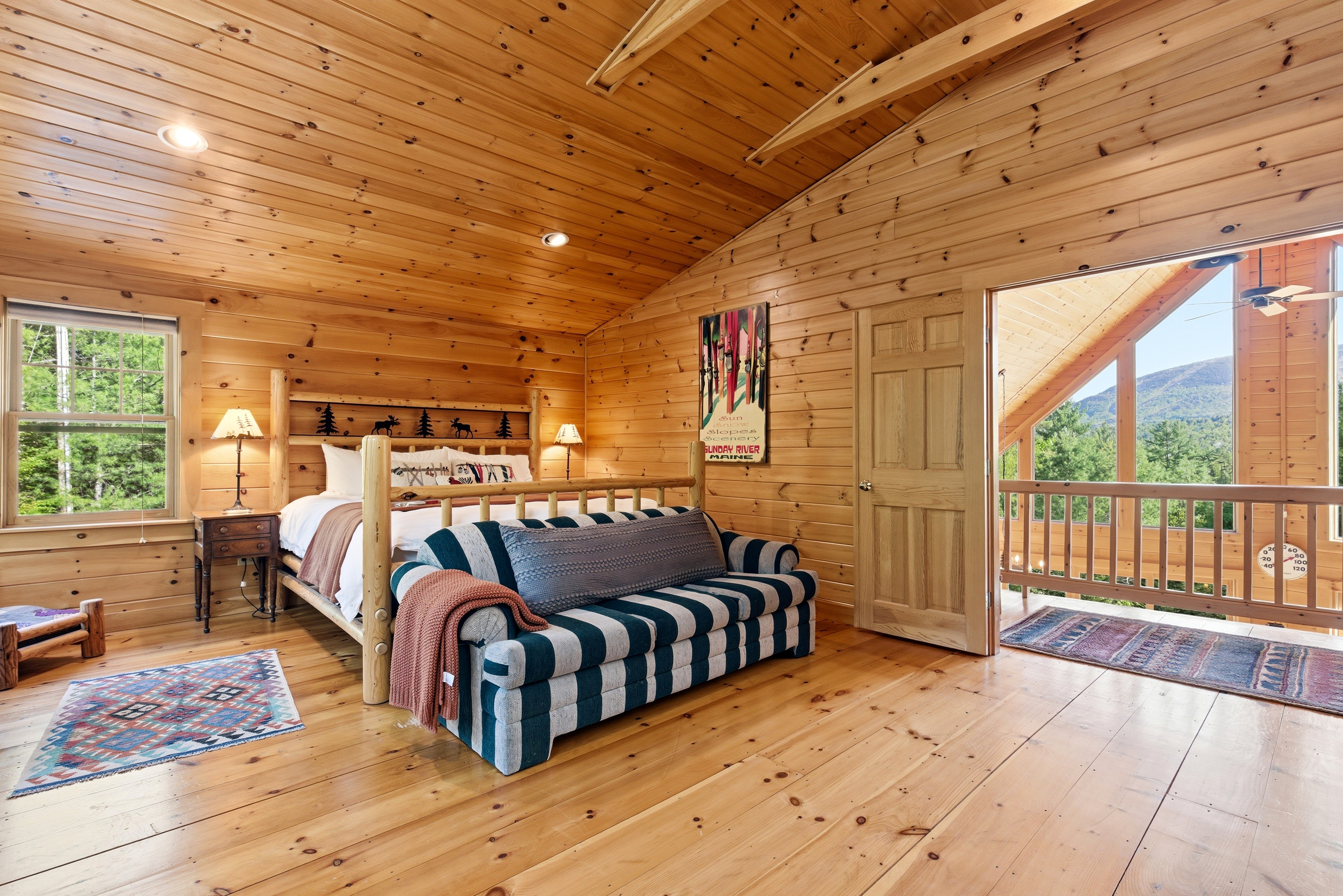 Spacious primary suite featuring soaring wood ceilings, cozy seating, and direct access to scenic views.