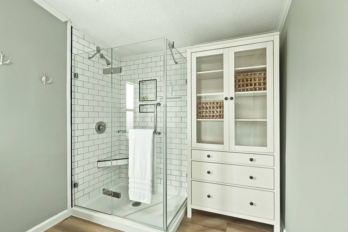 Step into the glass-enclosed walk-in shower, with built-in shelving nearby for convenient bathroom storage during your stay.