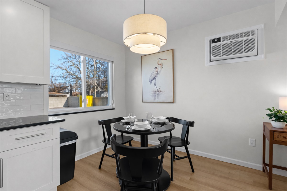 Modern dining area with stylish lighting, seating for four, and natural light—perfect for relaxed meals, morning coffee, or casual evenings together.