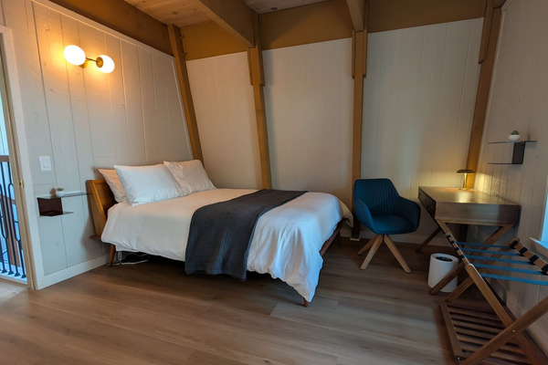 This modern A-frame room pairs a plush bed with a remote-ready desk setup and a convenient luggage rack.