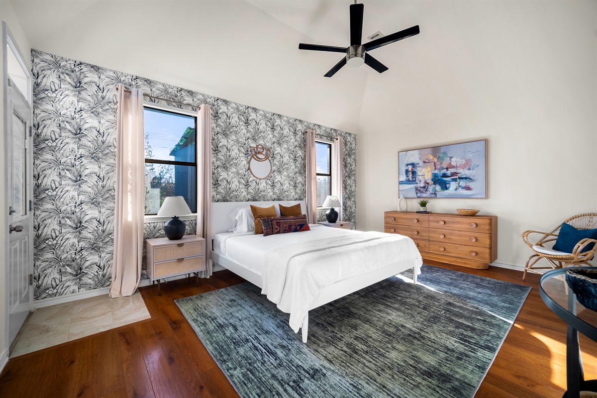 Spacious primary bedroom featuring a king-size bed, warm wooden floors, cozy carpet, and stylish wallpaper.