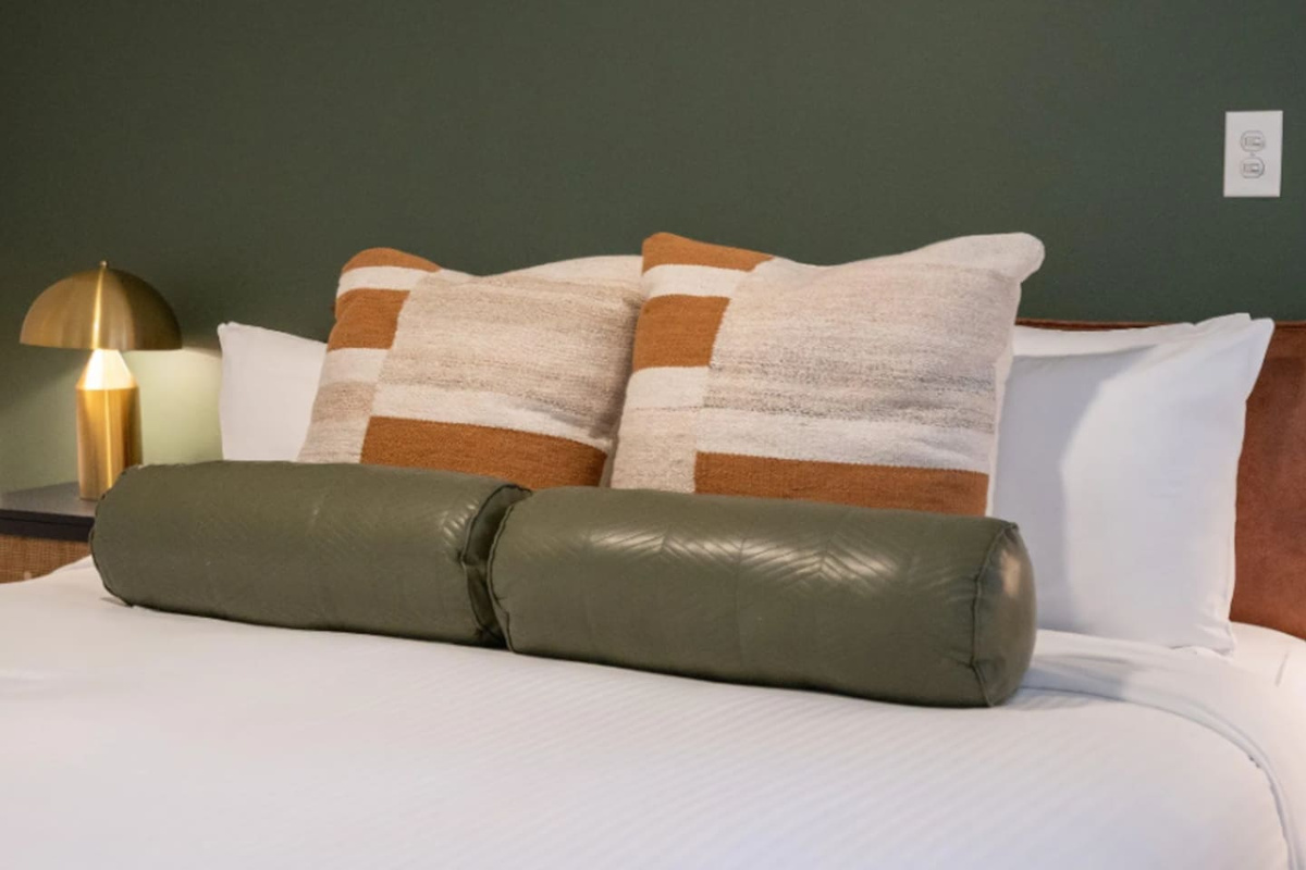 A brass lamp and deep green wall bring warmth and texture to this quiet corner of the bedroom.
