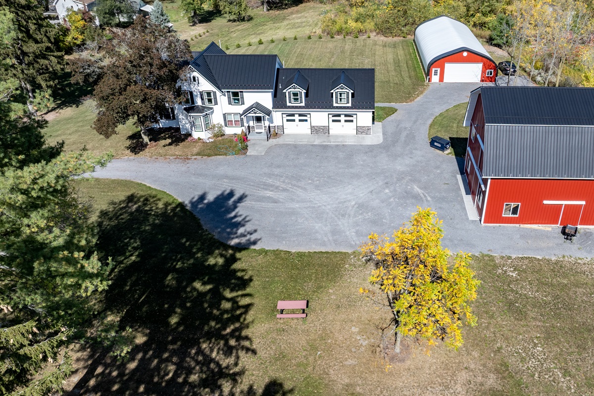 Modern farmhouse meets country serenity with red barn, open fields, and inviting drive-up appeal