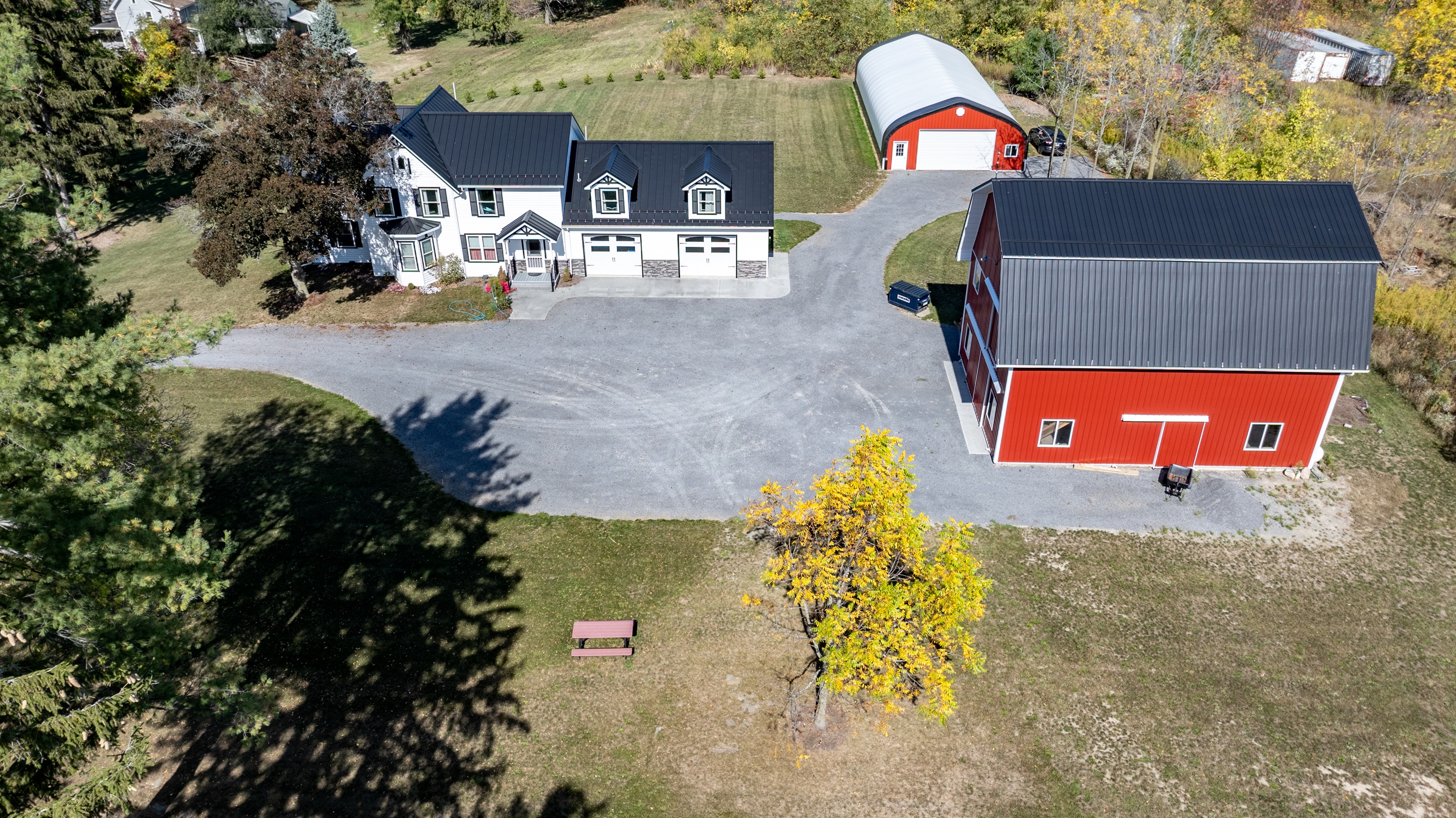 Modern farmhouse meets country serenity with red barn, open fields, and inviting drive-up appeal
